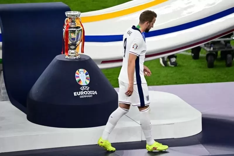 Striker timnas Inggris Harry Kane berjalan melewati trofi Piala Eropa setelah laga final Euro antara Spanyol dan Inggris di Stadion Olimpiade, Berlin, pada 14 Juli 2024. (AFP/TOBIAS SCHWARZ) 